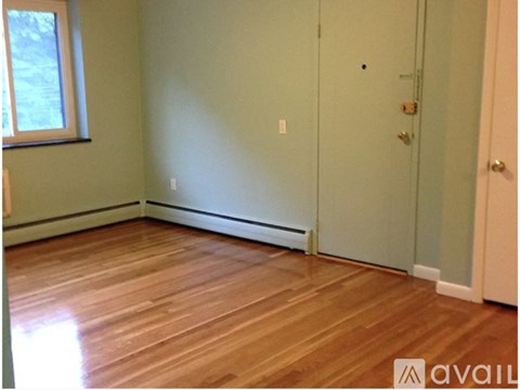 A room with wooden flooring and a door on the right side.
