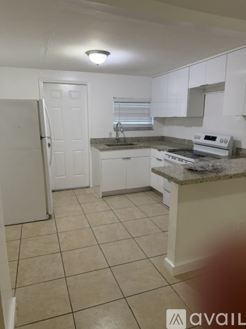 A kitchen with white cabinets and a granite countertop.