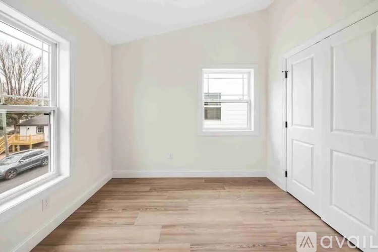 A room with a white door and a window with a view of a parking lot.