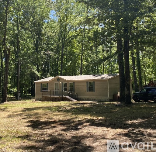 A small house is surrounded by trees in a wooded area.