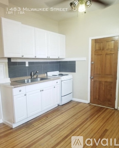 A kitchen with white cabinets and a wooden door.