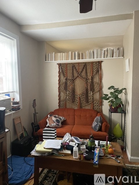 A living room with a brown couch and a coffee table with various items on it.