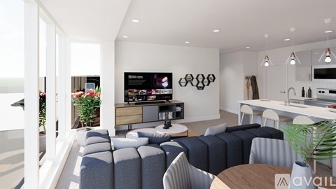 A modern living room with a large grey sofa and a television mounted on the wall.