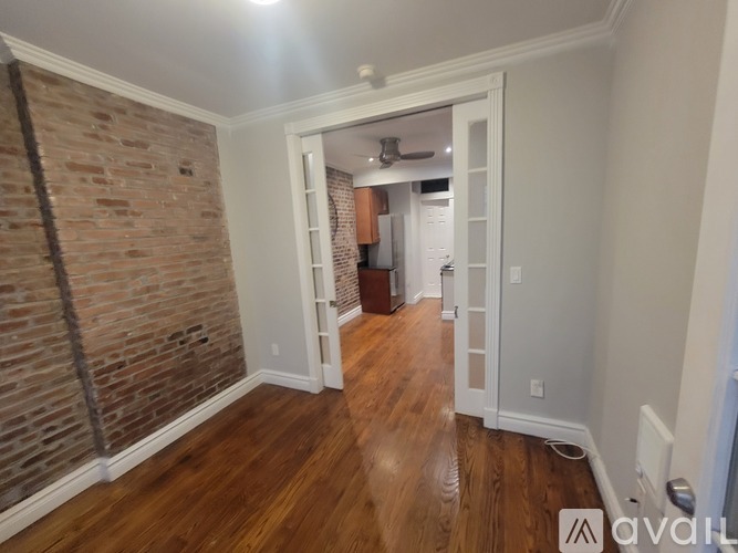 A hallway with a brick wall on the left and a white door on the right.