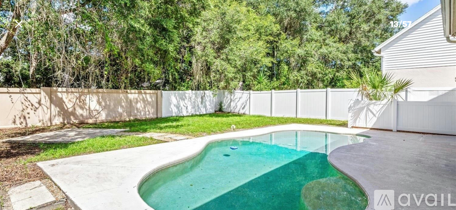 A small pool in a backyard surrounded by a white fence.