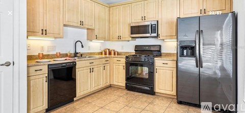 A kitchen with wooden cabinets and a black fridge.