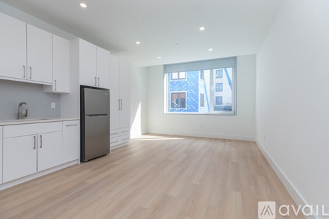 A kitchen with white cabinets and a black fridge.