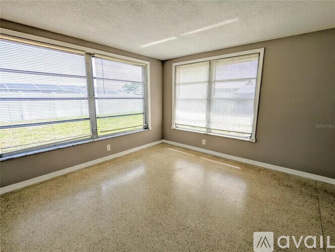 A room with a large window and a view of a fence and trees outside.