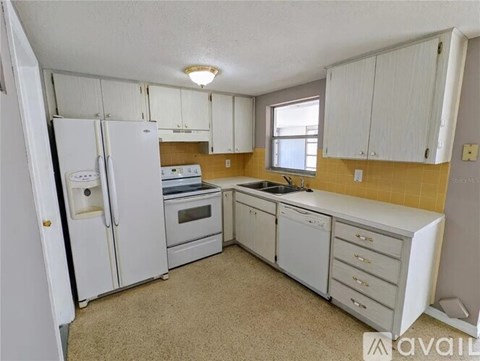 A kitchen with white appliances and cabinets.