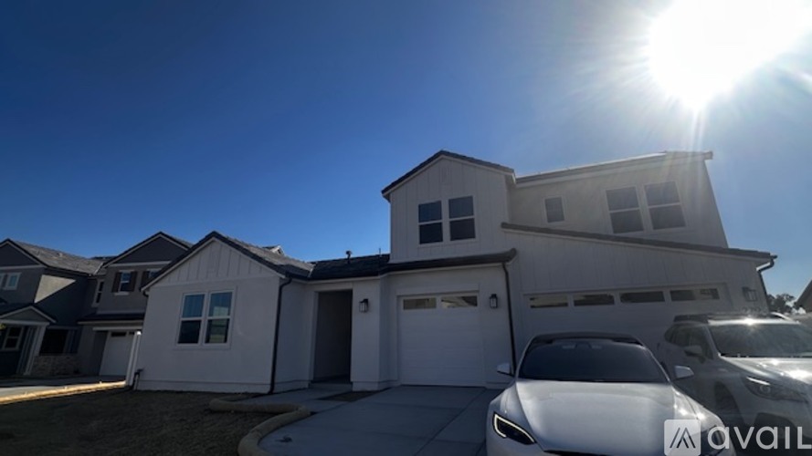 A house with a car parked in front and a sunny sky.