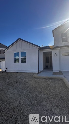 A small white house with a gravel driveway in front.