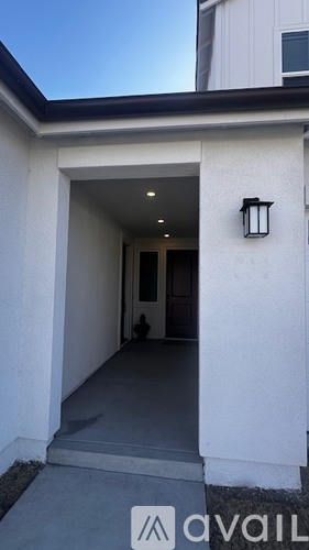 A white building with a black roof and a black lantern on the wall.