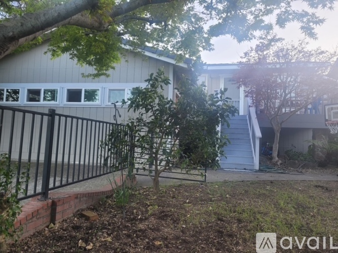 A house with a fence and a tree in front of it.