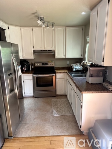 A kitchen with white cabinets and a refrigerator.
