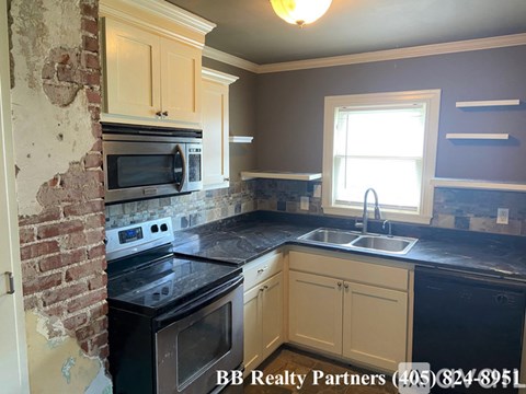 A kitchen with a brick wall and a black counter top.