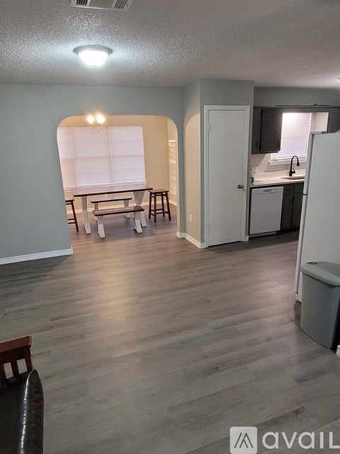 A kitchen area with a refrigerator, sink, and a dining table with chairs.