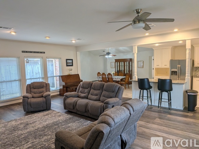 A living room with a grey sofa, two chairs and a piano.
