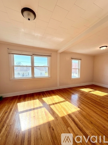 A room with wooden floors and two windows.