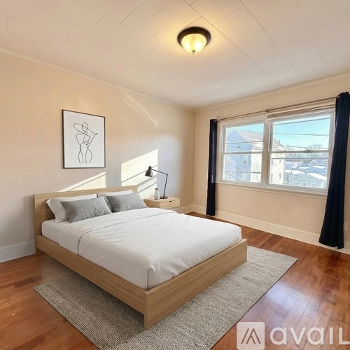 A bedroom with a large bed and a window with a view of buildings outside.