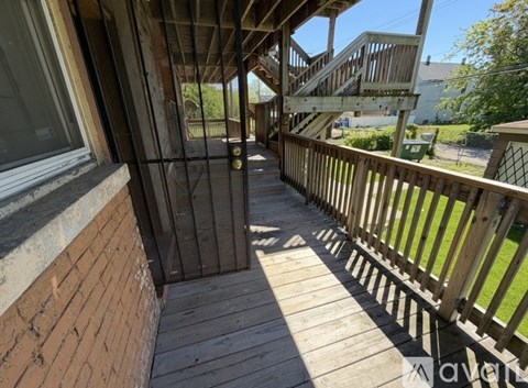 A wooden deck with a metal gate leading to a house.