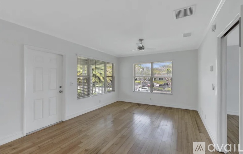A spacious room with wooden floors and a ceiling fan.