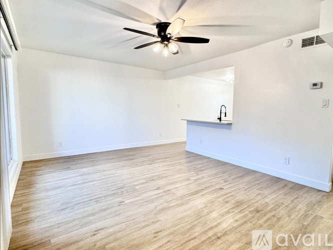 A spacious room with a ceiling fan and wooden flooring.