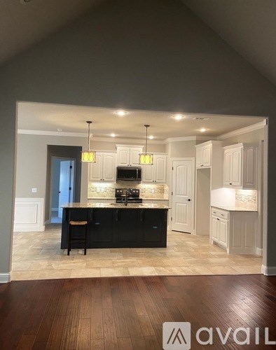 A kitchen with black cabinets and a wooden floor.