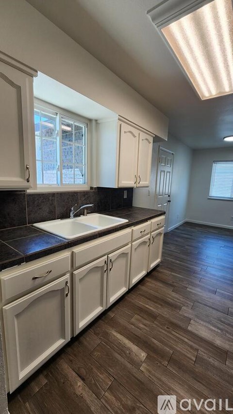 A kitchen with white cabinets and a black countertop.