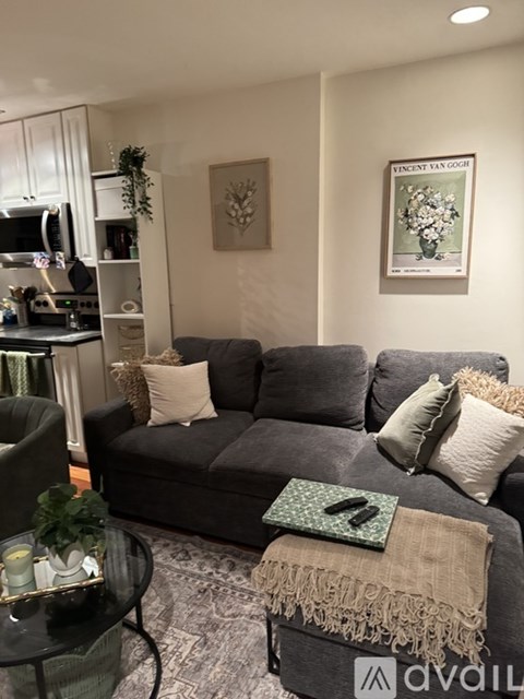 A living room with a grey couch and a glass coffee table.