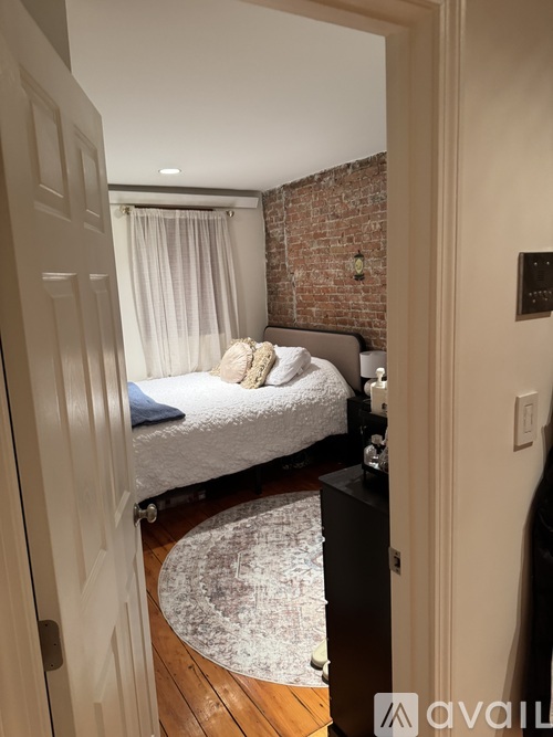 A bedroom with a brick wall and a bed with white bedding.