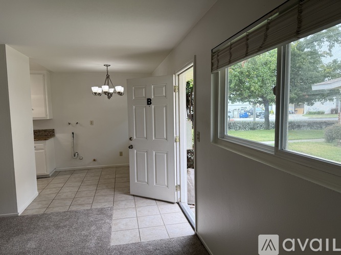 A room with a white door and a window with a view of a parking lot.