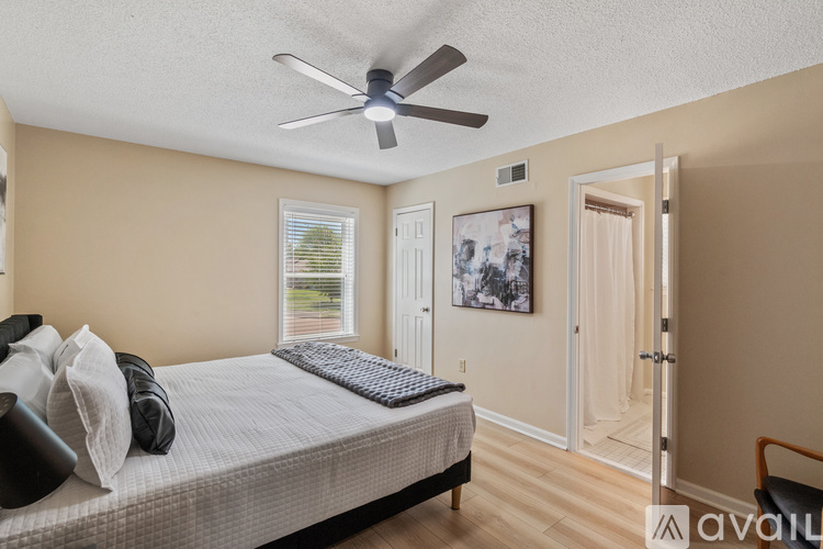 A bedroom with a bed, a ceiling fan, and a door leading to another room.