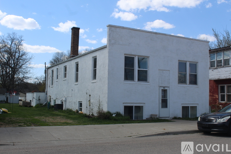 A white building with a black car parked in front of it.
