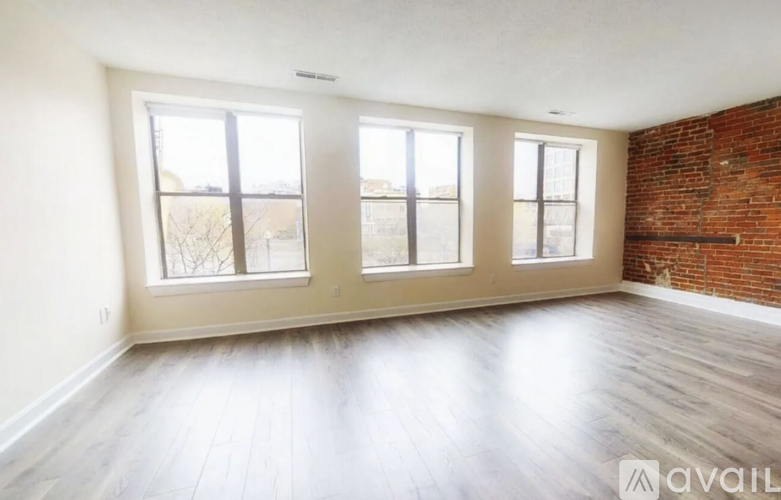 A room with wooden floors and three windows.