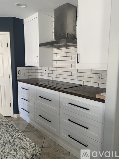 A kitchen with white cabinets and a black countertop.