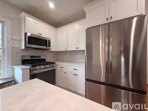 A kitchen with a stainless steel refrigerator and white cabinets.