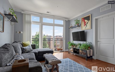 A living room with a grey couch and a television on the wall.