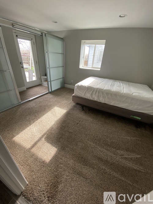 A bedroom with a bed, carpet, and a window.