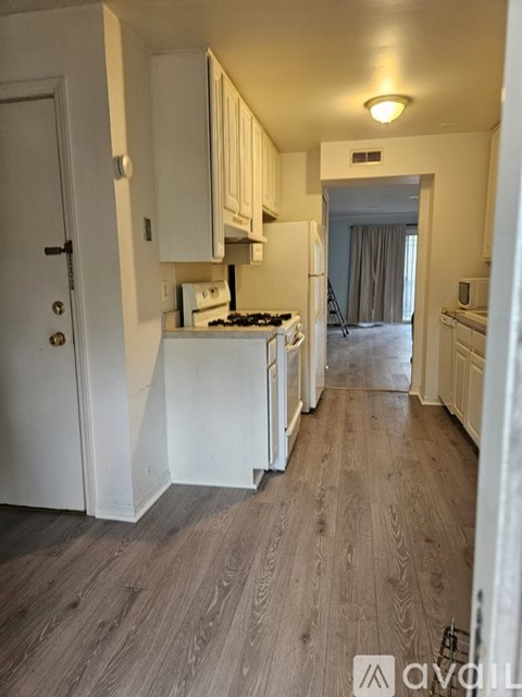 A kitchen with white cabinets and a wooden floor.
