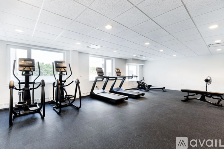 A gym with treadmills, elliptical machines, and a bench.