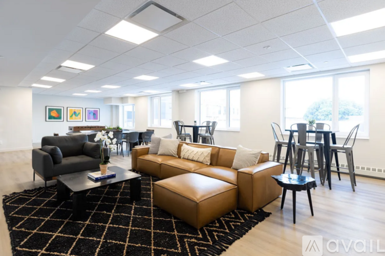 A living room with a black and white rug and brown leather furniture.