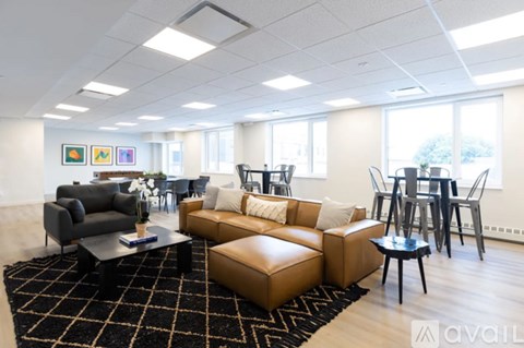 A living room with a black and white rug and brown leather furniture.