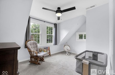 A living room with a rocking chair and a baby crib.