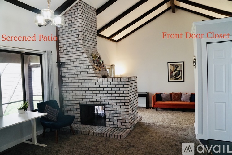 A living room with a brick fireplace and a screened patio.