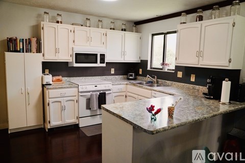 A kitchen with white cabinets and a granite countertop.