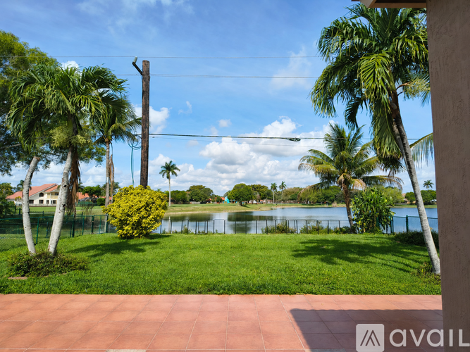 A view of a lake surrounded by palm trees and a clear blue sky.