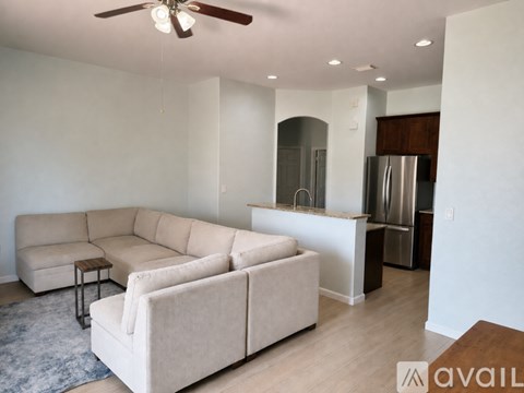 A living room with a beige couch and a ceiling fan.