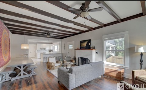 A living room with a grey couch and a white fireplace.