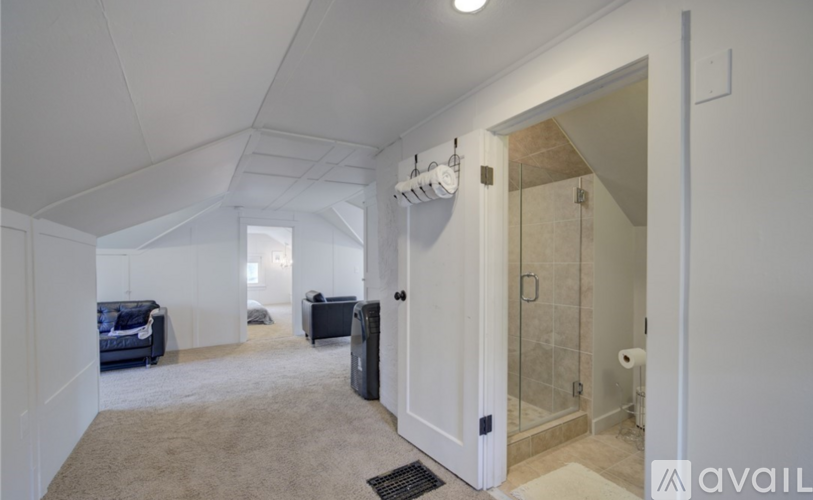 A spacious room with a couch, chair, and a shower area.