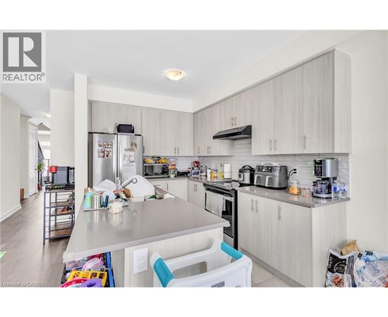 A kitchen with white cabinets and appliances, and a dining table with chairs.